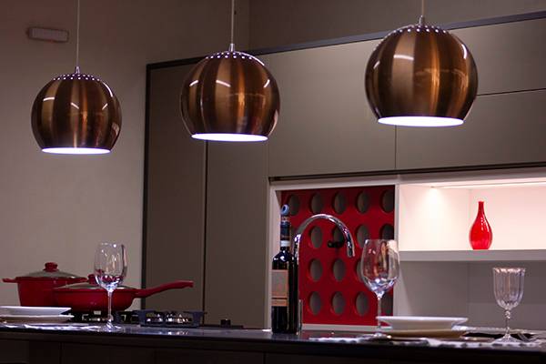 Cozinha planejada com pendentes metálicos e detalhe em vermelho
